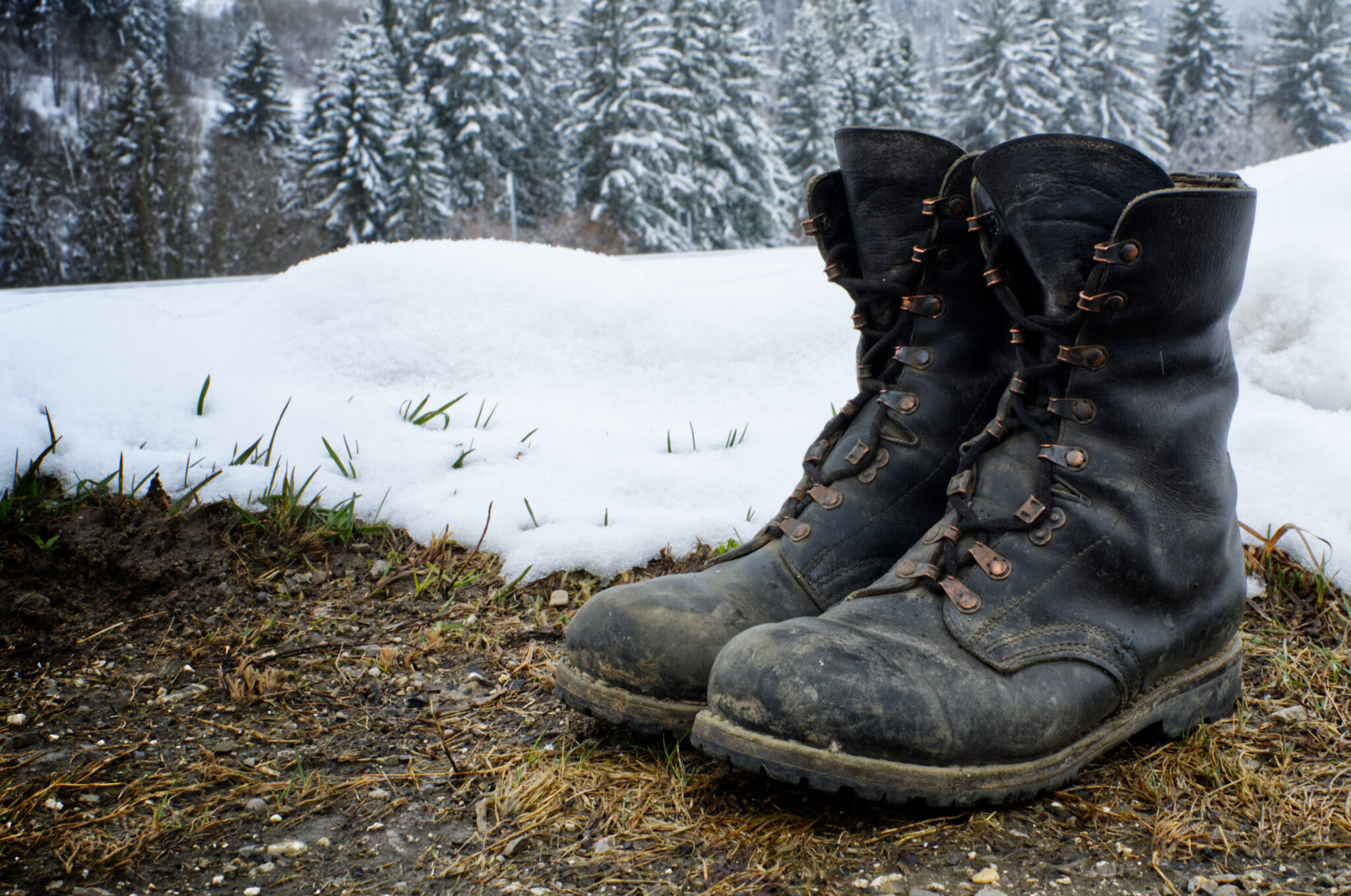 Ein Paar Armeestiefel, die vor einer Schneelandschaft stehen.